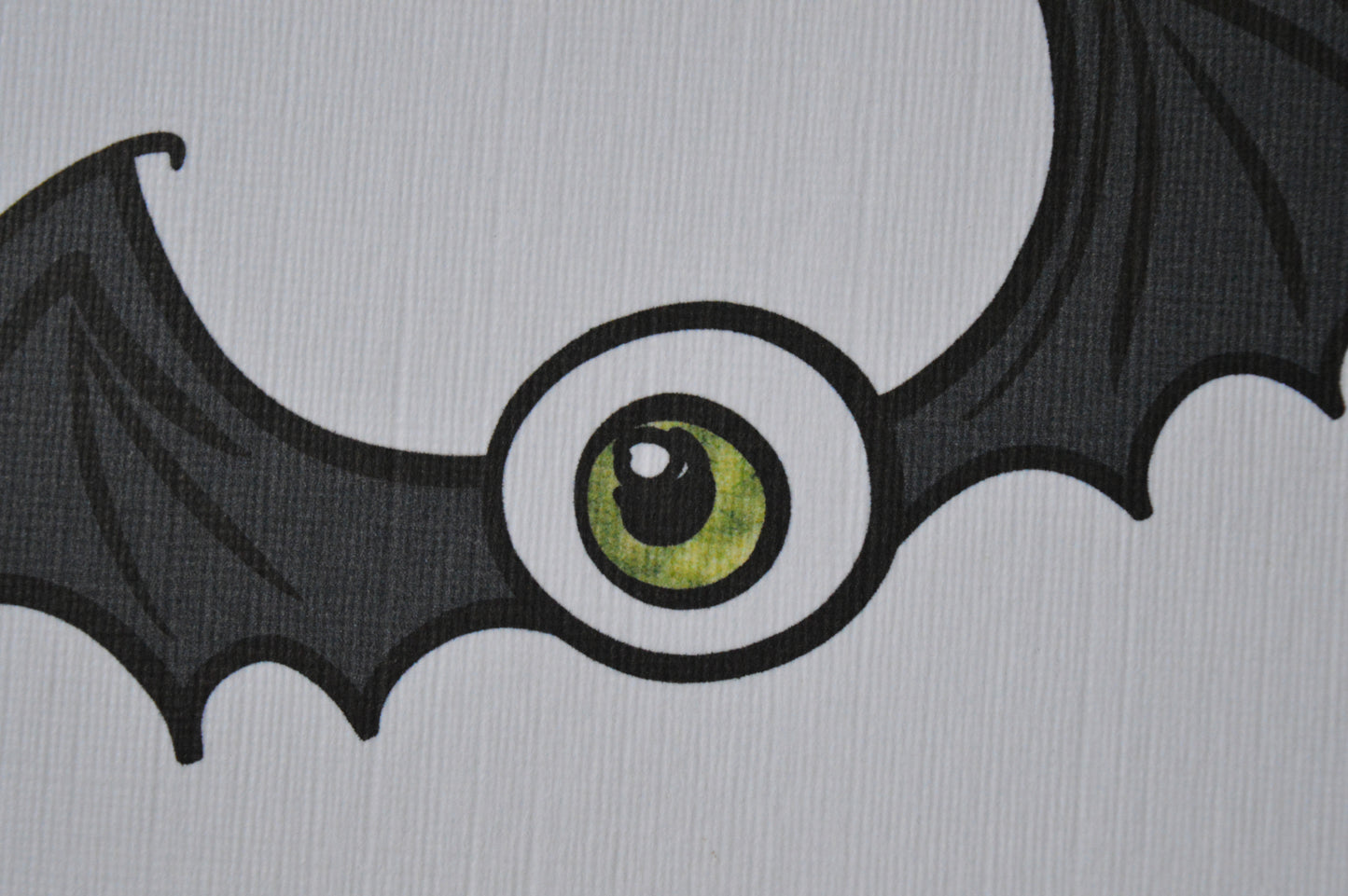 Bat wings with a large green eye in the centre