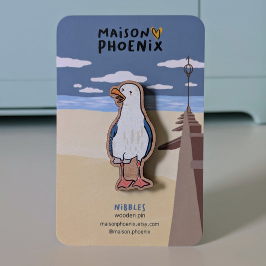 Wooden pin of a seagull on a card with 'Maison Phoenix' branding